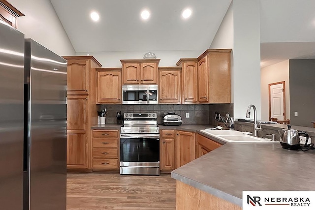 21204 Hampton Dr, Gretna, NE 68028 - kitchen with stainless steel appliances, a sink, lofted ceiling, light wood-style flooring, and tasteful backsplash