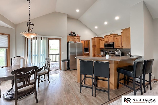 21204 Hampton Dr, Gretna, NE 68028 - kitchen with stainless steel appliances, a peninsula, high vaulted ceiling, light wood finished floors, and a kitchen breakfast bar