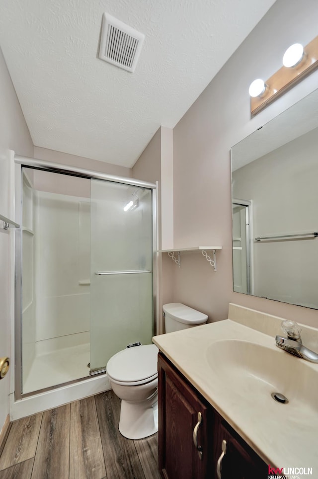 235 W Belmont Ave, Lincoln, NE 68521 - bathroom featuring vanity, wood finished floors, a stall shower, toilet, and a textured ceiling