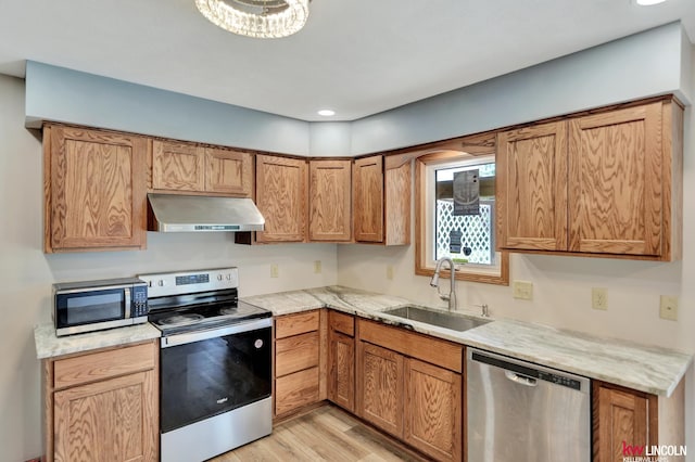 235 W Belmont Ave, Lincoln, NE 68521 - kitchen with under cabinet range hood, appliances with stainless steel finishes, a sink, light wood-style flooring, and brown cabinets