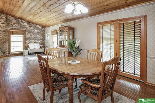 9706 N 51st St, Omaha, NE 68152 - dining space featuring a chandelier, vaulted ceiling, wood-type flooring, brick wall, and wallpapered walls