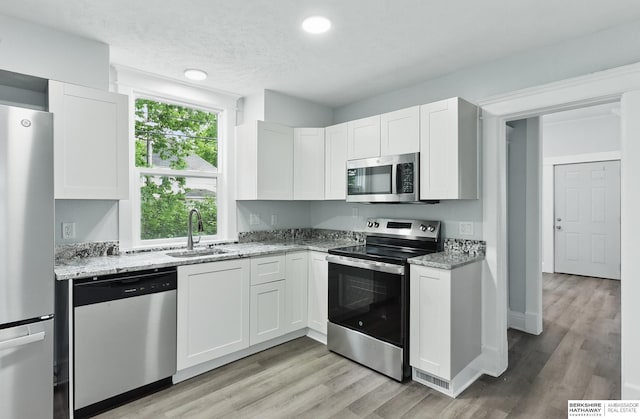 2909 N 26th St, Omaha, NE 68111 - kitchen featuring stainless steel appliances, a sink, light stone countertops, light wood finished floors, and recessed lighting