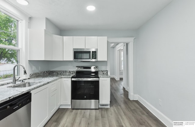 2909 N 26th St, Omaha, NE 68111 - kitchen with appliances with stainless steel finishes, a sink, white cabinets, and plenty of natural light