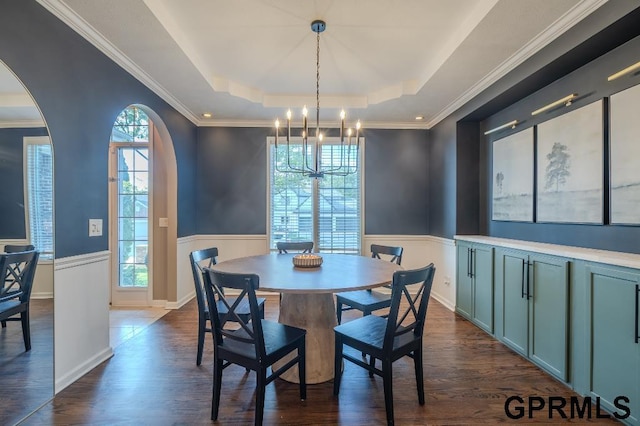 15931 Yates St, Omaha, NE 68116 - dining space with a chandelier, a tray ceiling, wainscoting, dark wood-style flooring, and arched walkways