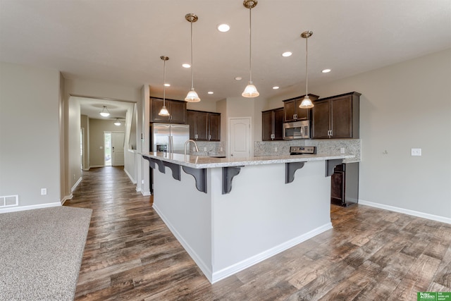 4604 Hansen Ave, Papillion, NE 68133 - kitchen featuring stainless steel appliances, dark brown cabinets, backsplash, a breakfast bar, and recessed lighting