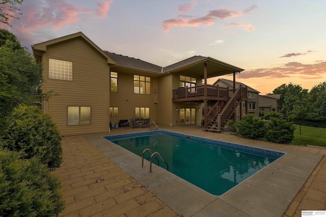 14906 Hanover St, Bennington, NE 68007 - pool at dusk featuring stairway, a wooden deck, a patio, and an outdoor pool
