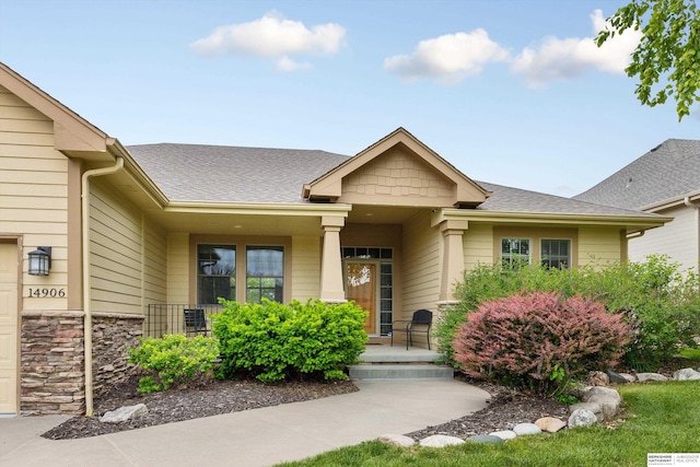 14906 Hanover St, Bennington, NE 68007 - property entrance featuring covered porch, stone siding, roof with shingles, and a garage