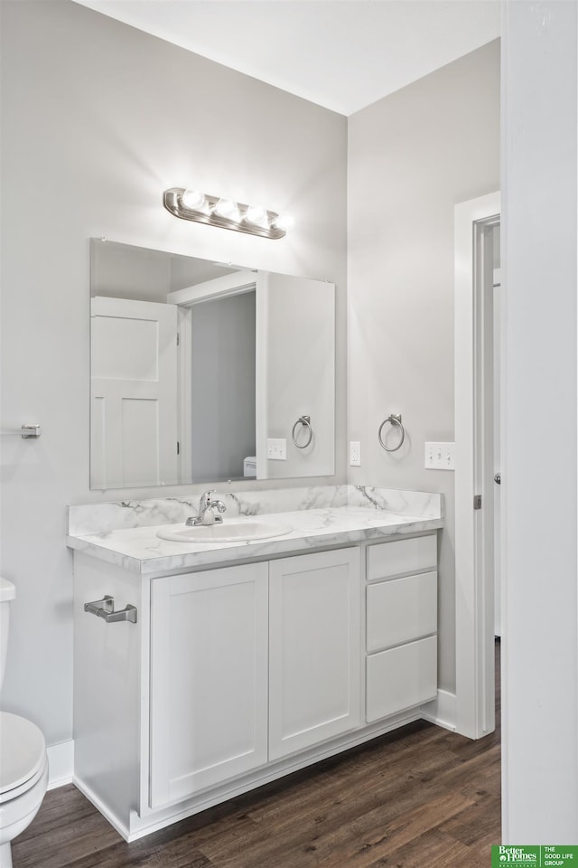 2273 N 38th Ave, Omaha, NE 68111 - bathroom featuring double vanity, toilet, wood finished floors, and baseboards