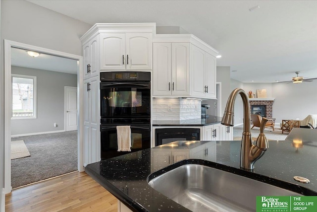 16831 Chandler St, Omaha, NE 68136 - kitchen with a brick fireplace, a sink, dark stone countertops, white cabinetry, and recessed lighting