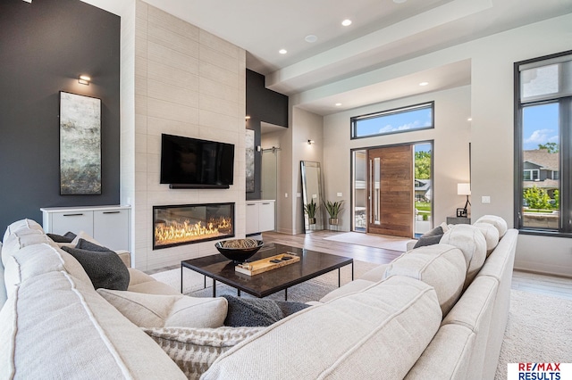 1520 S 218th St, Elkhorn, NE 68022 - living area with recessed lighting, a towering ceiling, a tiled fireplace, light wood-type flooring, and baseboards
