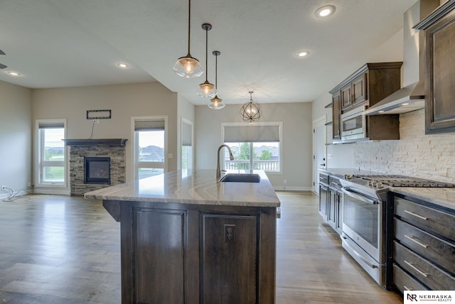 11051 Edgewater Dr, Papillion, NE 68046 - kitchen with stainless steel appliances, a sink, wall chimney exhaust hood, light wood-style flooring, and tasteful backsplash