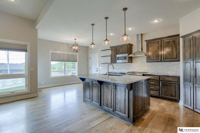 11051 Edgewater Dr, Papillion, NE 68046 - kitchen featuring wall chimney range hood, stainless steel microwave, a sink, light wood-type flooring, and decorative backsplash