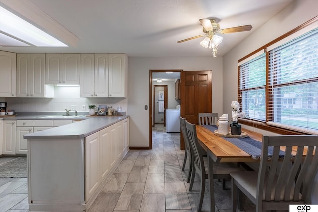 12212 Leavenworth Rd, Omaha, NE 68154 - kitchen featuring a peninsula, white cabinetry, a sink, and ceiling fan
