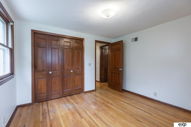 12212 Leavenworth Rd, Omaha, NE 68154 - unfurnished bedroom featuring light wood-type flooring, baseboards, multiple windows, and a closet