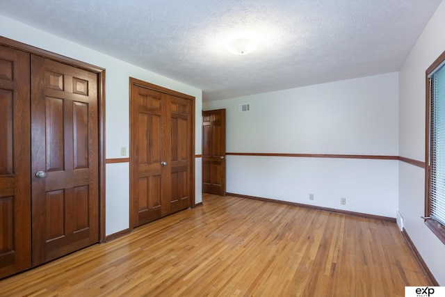 12212 Leavenworth Rd, Omaha, NE 68154 - unfurnished bedroom with light wood-style floors, baseboards, and a textured ceiling