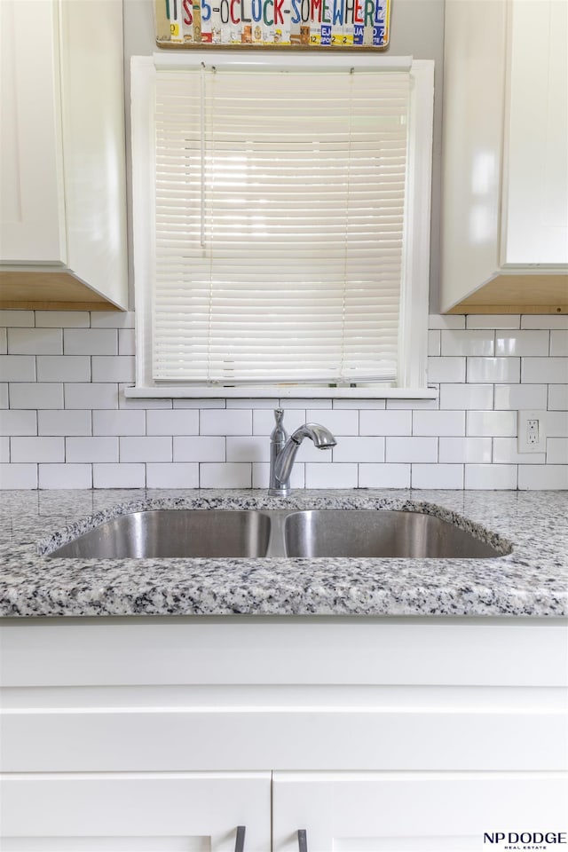 3185 Stone Ave, Omaha, NE 68111 - kitchen with a sink, decorative backsplash, white cabinets, and light stone counters
