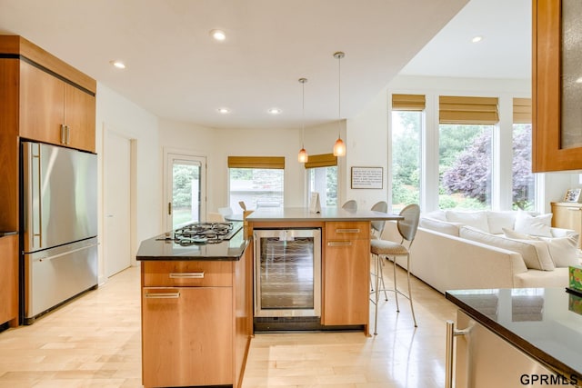 6500 Pheasant Run Ct, Lincoln, NE 68516 - kitchen featuring freestanding refrigerator, wine cooler, gas stovetop, light wood-style flooring, and a kitchen bar