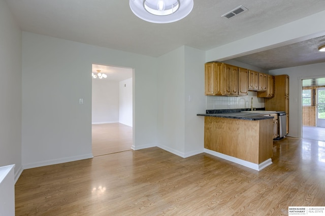 3121 State St, Omaha, NE 68112 - kitchen with light wood-style flooring, tasteful backsplash, dark countertops, a peninsula, and brown cabinetry
