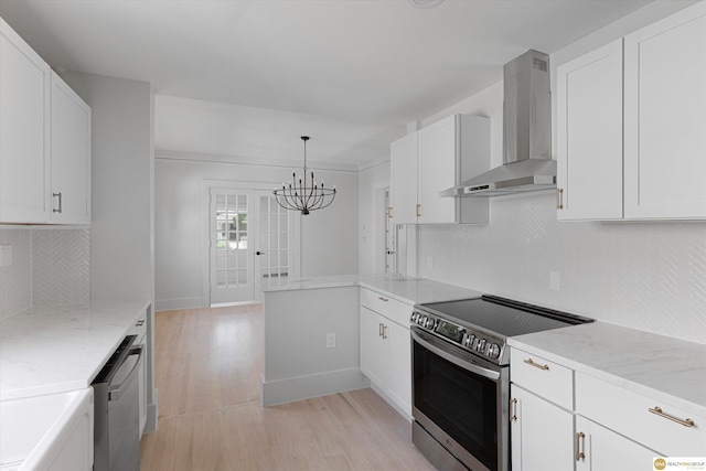5009 Burt St, Omaha, NE 68132 - kitchen with appliances with stainless steel finishes, wall chimney exhaust hood, a chandelier, light wood finished floors, and white cabinets