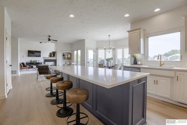 9711 S 176th St, Omaha, NE 68136 - kitchen with a sink, a kitchen breakfast bar, a fireplace, a ceiling fan, and light wood finished floors