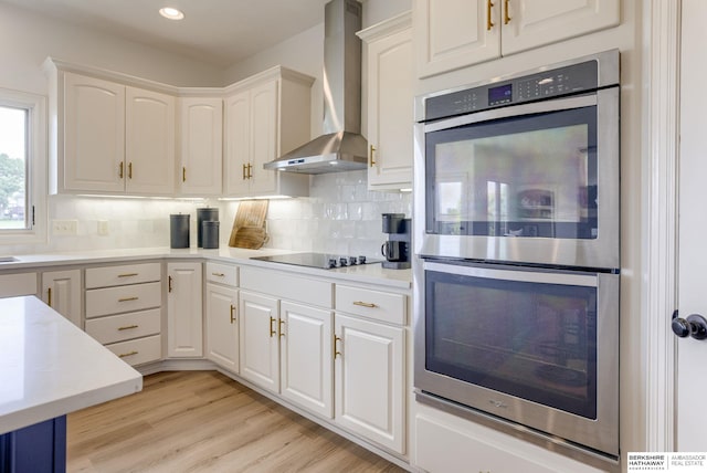 9711 S 176th St, Omaha, NE 68136 - kitchen with wall chimney exhaust hood, double oven, black electric cooktop, white cabinetry, and backsplash