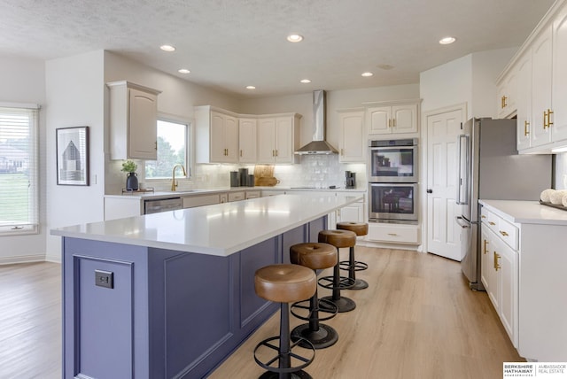 9711 S 176th St, Omaha, NE 68136 - kitchen with wall chimney range hood, light wood-style floors, a kitchen breakfast bar, white cabinets, and recessed lighting