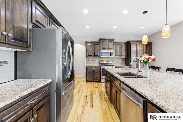 18402 Polk St, Omaha, NE 68135 - kitchen featuring appliances with stainless steel finishes, a sink, light wood finished floors, decorative light fixtures, and recessed lighting