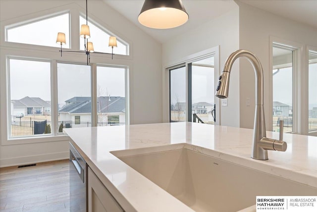 17018 Daniel St, Bennington, NE 68007 - kitchen with a sink, stainless steel dishwasher, light wood-type flooring, decorative light fixtures, and light stone counters