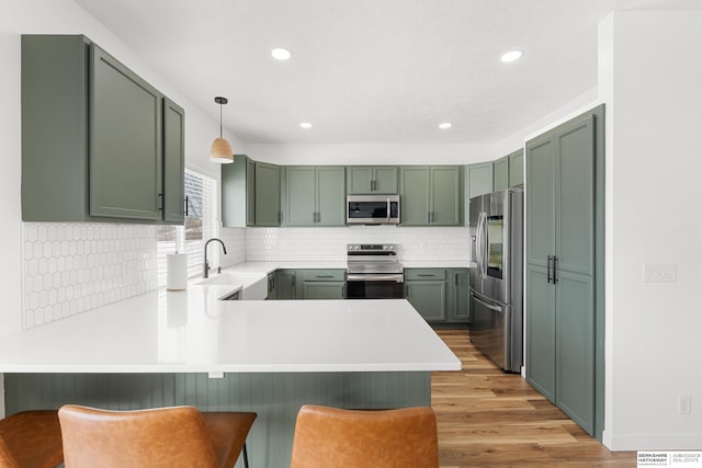 4706 S 187th Ave, Omaha, NE 68135 - kitchen with stainless steel appliances, green cabinetry, a peninsula, a sink, and recessed lighting