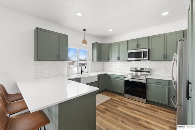 4706 S 187th Ave, Omaha, NE 68135 - kitchen with stainless steel appliances, a sink, a peninsula, light wood finished floors, and a breakfast bar area
