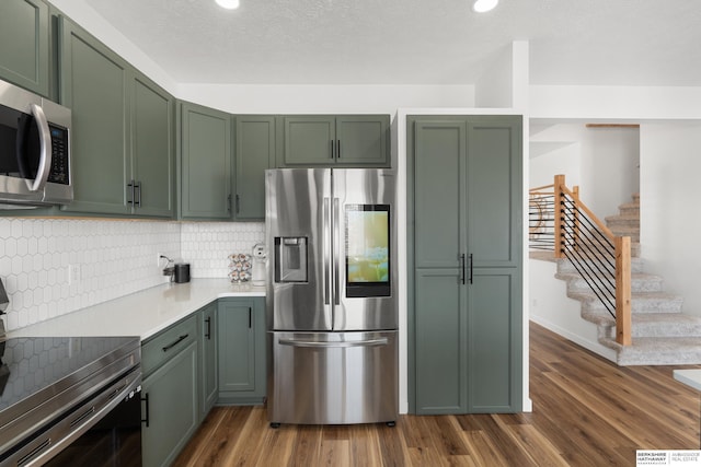 4706 S 187th Ave, Omaha, NE 68135 - kitchen featuring appliances with stainless steel finishes, green cabinets, dark wood-type flooring, tasteful backsplash, and recessed lighting