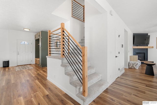 4706 S 187th Ave, Omaha, NE 68135 - stairs featuring wood finished floors, a glass covered fireplace, and baseboards