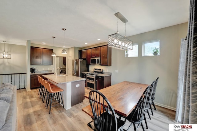 7237 Yankee Woods Dr, Lincoln, NE 68516 - kitchen featuring stainless steel appliances, a sink, a breakfast bar area, light wood-style floors, and dark brown cabinets