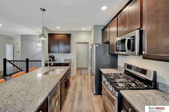 7237 Yankee Woods Dr, Lincoln, NE 68516 - kitchen featuring stainless steel appliances, a sink, light wood-style flooring, dark brown cabinetry, and pendant lighting