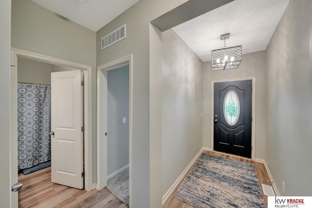 7237 Yankee Woods Dr, Lincoln, NE 68516 - foyer featuring light wood-style flooring, a chandelier, a textured ceiling, and baseboards