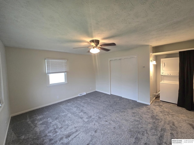 713 Janes View St, Papillion, NE 68046 - unfurnished bedroom with stacked washer / drying machine, dark carpet, baseboards, a closet, and a textured ceiling