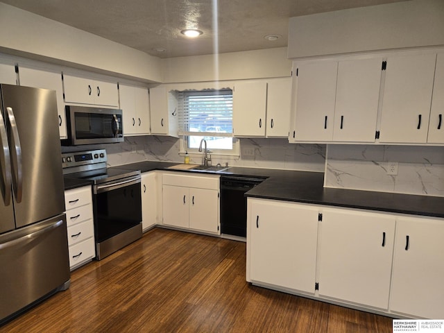 713 Janes View St, Papillion, NE 68046 - kitchen featuring stainless steel appliances, a sink, dark countertops, dark wood-style floors, and white cabinetry