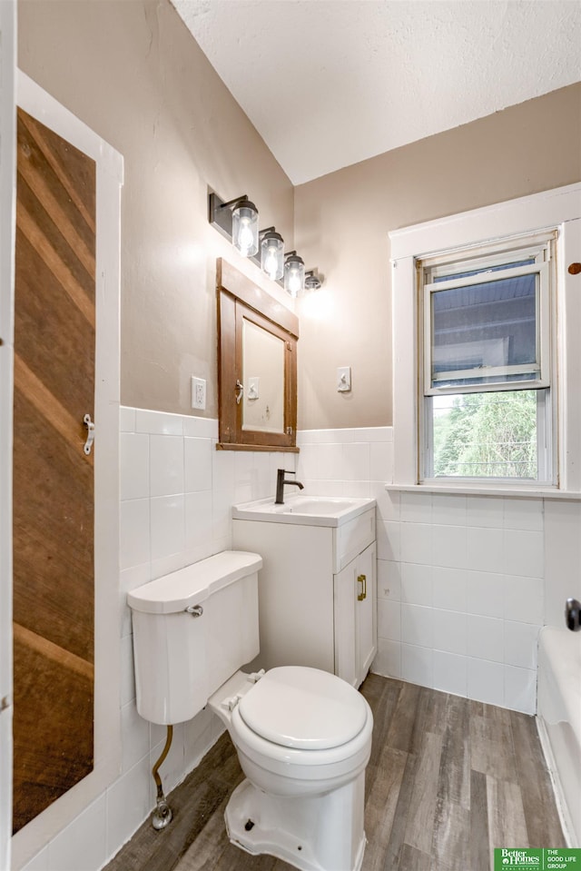 3520 N 55th St, Omaha, NE 68104 - bathroom with tile walls, toilet, wood finished floors, a bath, and wainscoting
