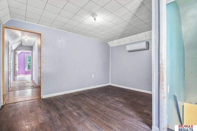 240 E 15th St, Fremont, NE 68025 - empty room with an AC wall unit, wood finished floors, vaulted ceiling, baseboards, and a pendent fire sprinkler