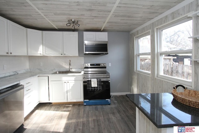 4530 N 72nd St, Lincoln, NE 68507 - kitchen featuring appliances with stainless steel finishes, a sink, dark wood-style floors, white cabinets, and baseboards