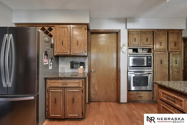 15708 Leavenworth St, Omaha, NE 68118 - kitchen with appliances with stainless steel finishes, light wood-style floors, brown cabinets, and dark stone countertops