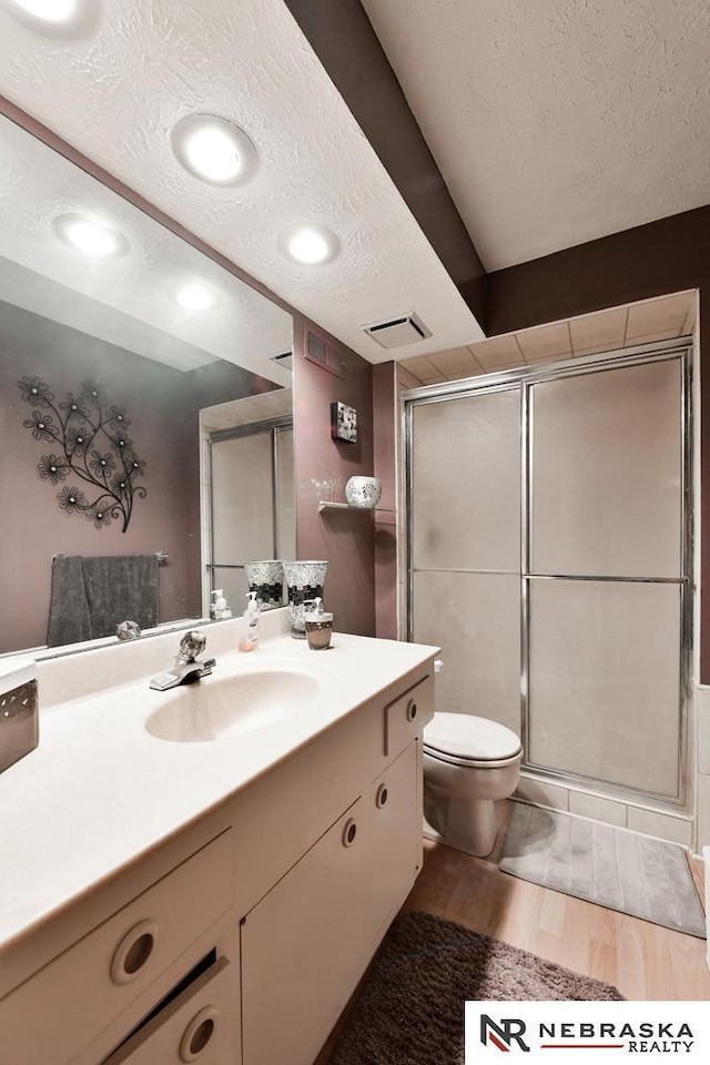 15708 Leavenworth St, Omaha, NE 68118 - full bathroom featuring a textured ceiling, vanity, wood finished floors, toilet, and a stall shower