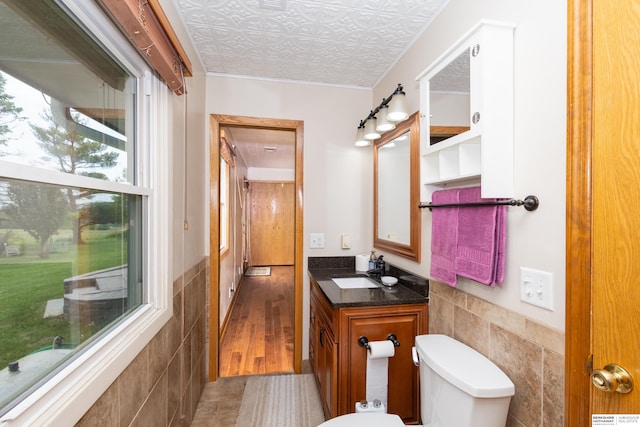 13205 N 192nd St, Bennington, NE 68007 - bathroom with tile walls, vanity, toilet, a wainscoted wall, and ornamental molding