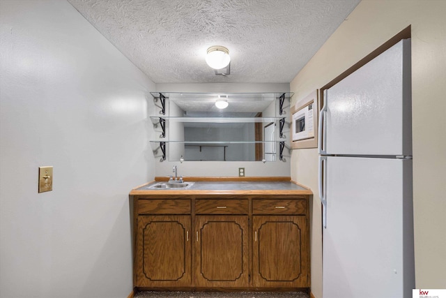14460 Patrick Ave, Omaha, NE 68116 - kitchen featuring white appliances, a sink, brown cabinets, a textured ceiling, and light countertops