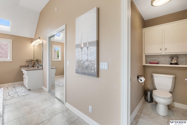 15921 Lake St, Omaha, NE 68116 - bathroom featuring toilet, vanity, marble finish flooring, lofted ceiling, and baseboards