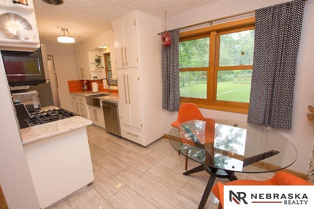 3840 X St, Lincoln, NE 68503 - kitchen featuring dishwasher, a sink, white cabinets, black microwave, and light tile patterned floors