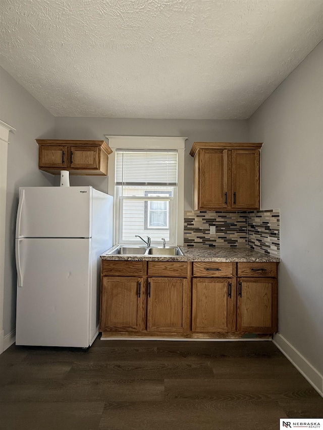 1322 S 21st St, Omaha, NE 68108 - kitchen with freestanding refrigerator, a sink, dark wood-style flooring, decorative backsplash, and a textured ceiling