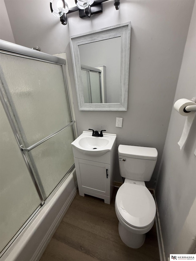 1322 S 21st St, Omaha, NE 68108 - bathroom featuring wood finished floors, vanity, bath / shower combo with glass door, toilet, and baseboards