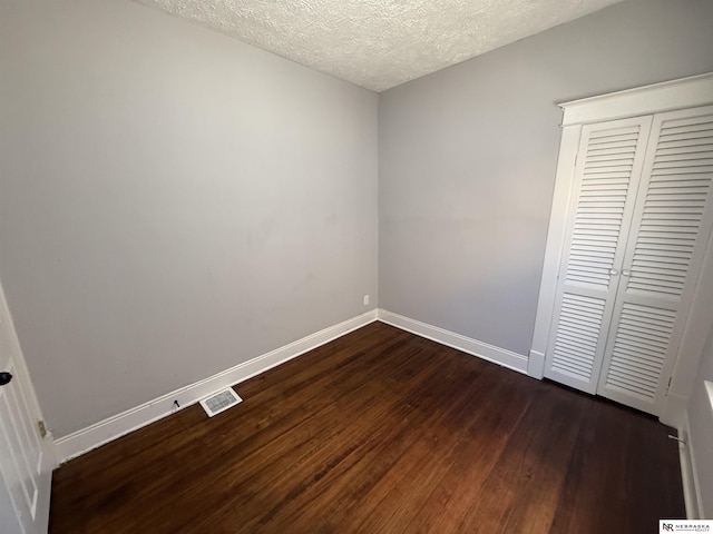 1322 S 21st St, Omaha, NE 68108 - unfurnished bedroom featuring dark wood-style floors, baseboards, a closet, and a textured ceiling