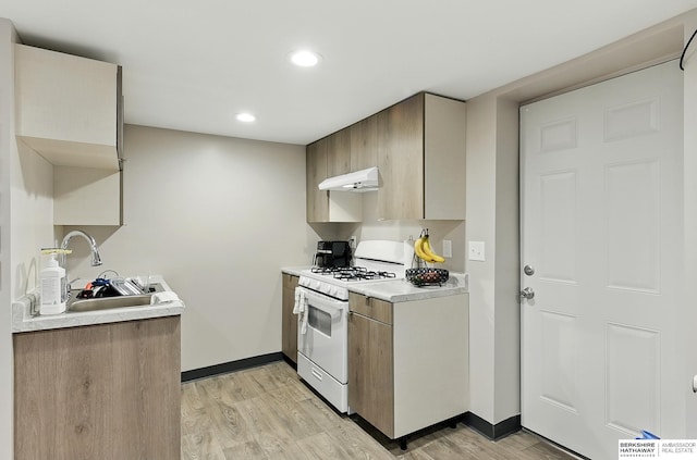 115 N 38th Ave, Omaha, NE 68131 - kitchen featuring white gas range oven, under cabinet range hood, light countertops, light wood-style flooring, and recessed lighting